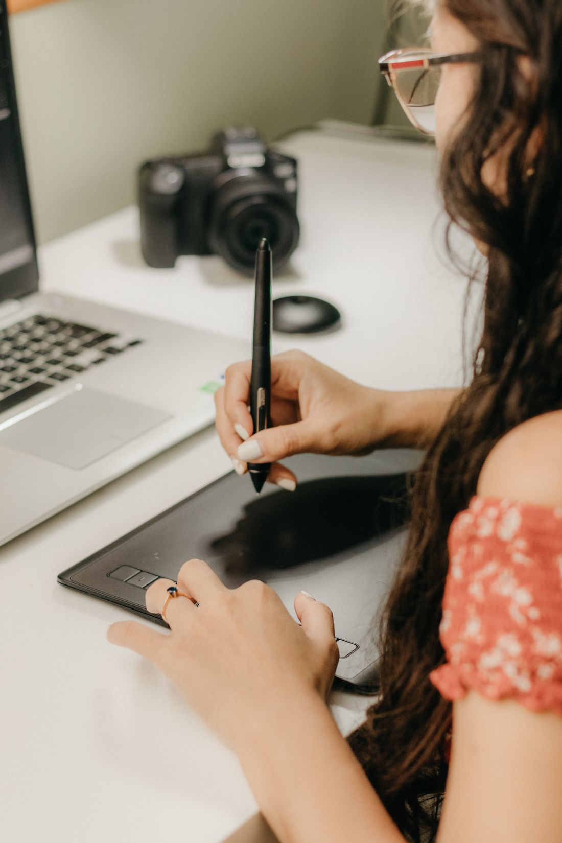 A graphic designer using a tablet and laptop in a workspace.